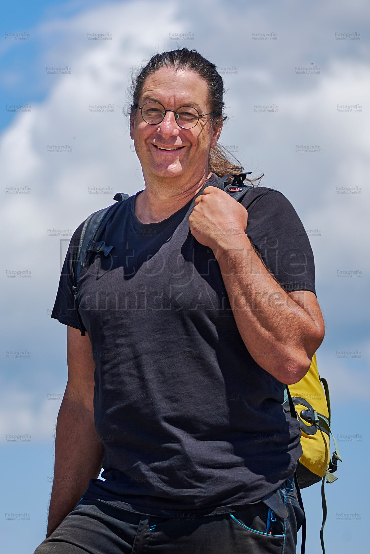Yannick Andrea mit Rucksack in den Bergen unterwegs.